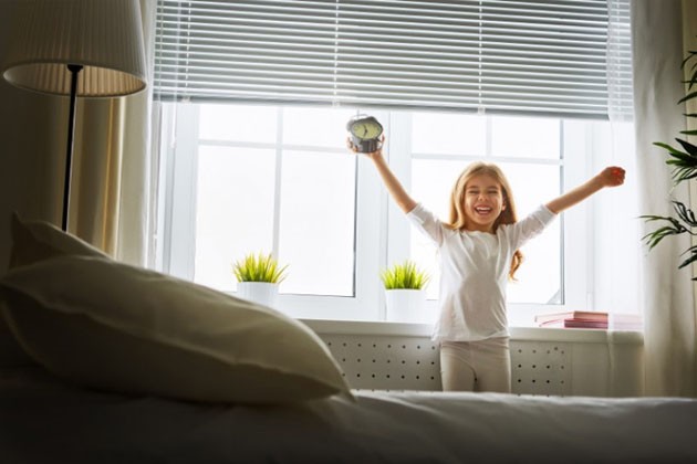 A child standing in front of a window and excitedly holding up a clock on Leap Year day