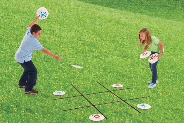 Kids playing tic tac toe with paper plates decorated with x’s and o’s.